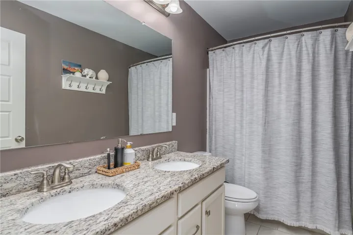 Double vanity with stone counters provides ample space in this well-appointed bathroom.