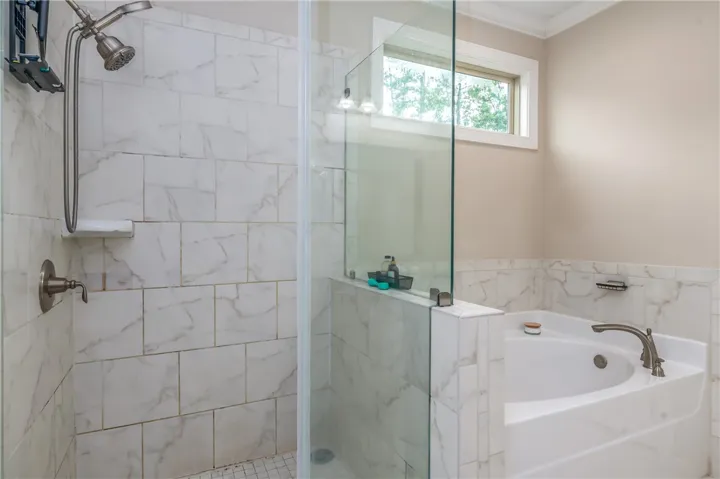 Step into a generously sized primary bathroom featuring a tiled walk-in shower and a built-in soaking tub.