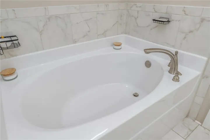 Indulge in relaxation within this generously sized soaking tub, featuring elegant brushed nickel fixtures and surrounding tilework.