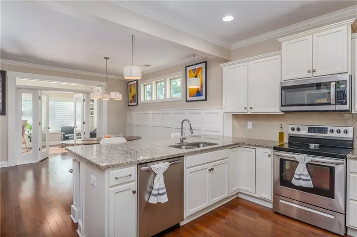 A well-appointed kitchen features rich hardwood flooring and sleek stainless steel appliances, opening to a sun-drenched dining area.