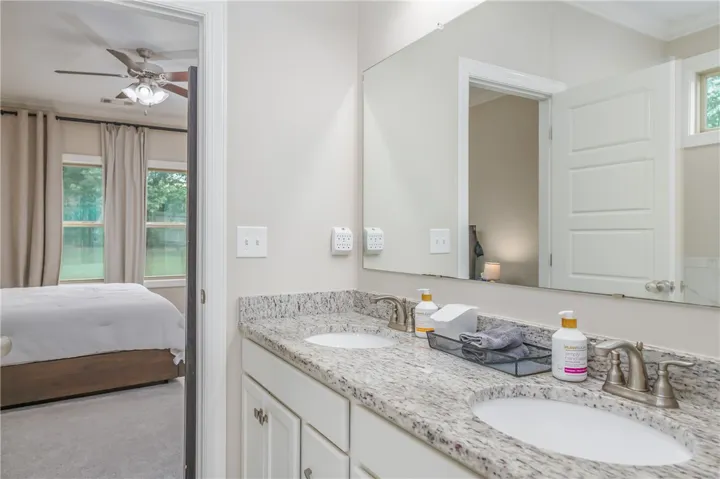 Double vanity with stone countertops offers convenience and style in this connecting bathroom.