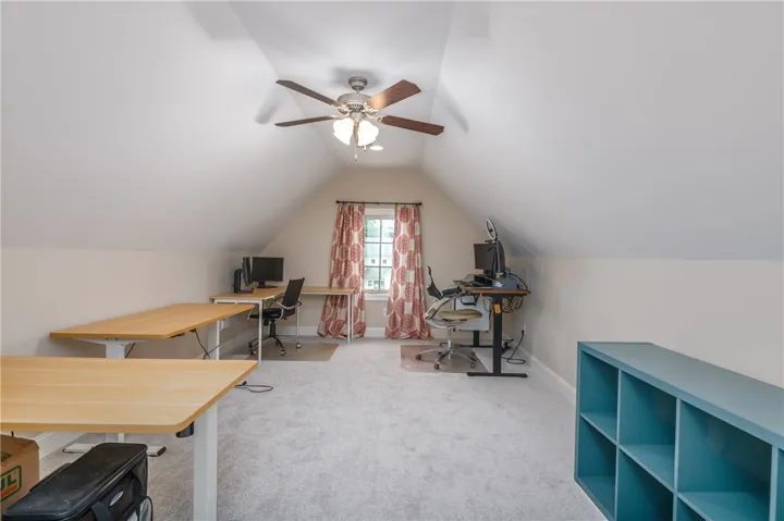 A versatile loft space, perfect for dual home offices, features sloped ceilings and ample natural light from a central window.