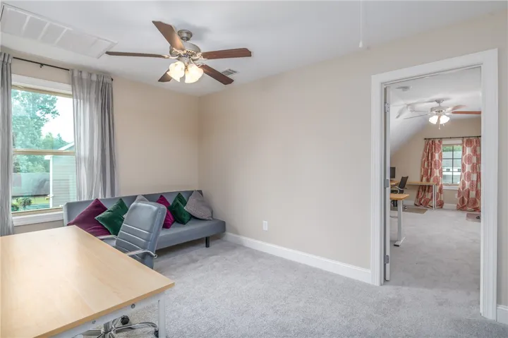 A versatile office space provides comfort and functionality with carpet flooring and ample natural light.