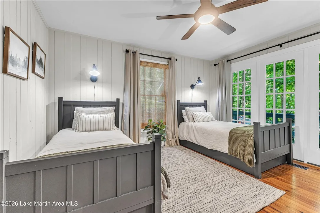 Two individual beds offer peaceful slumber within this charming bedroom featuring hardwood floors and direct outdoor access.