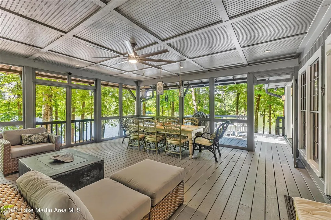 A spacious screened porch overlooks serene waters and lush woodlands, perfect for outdoor living.