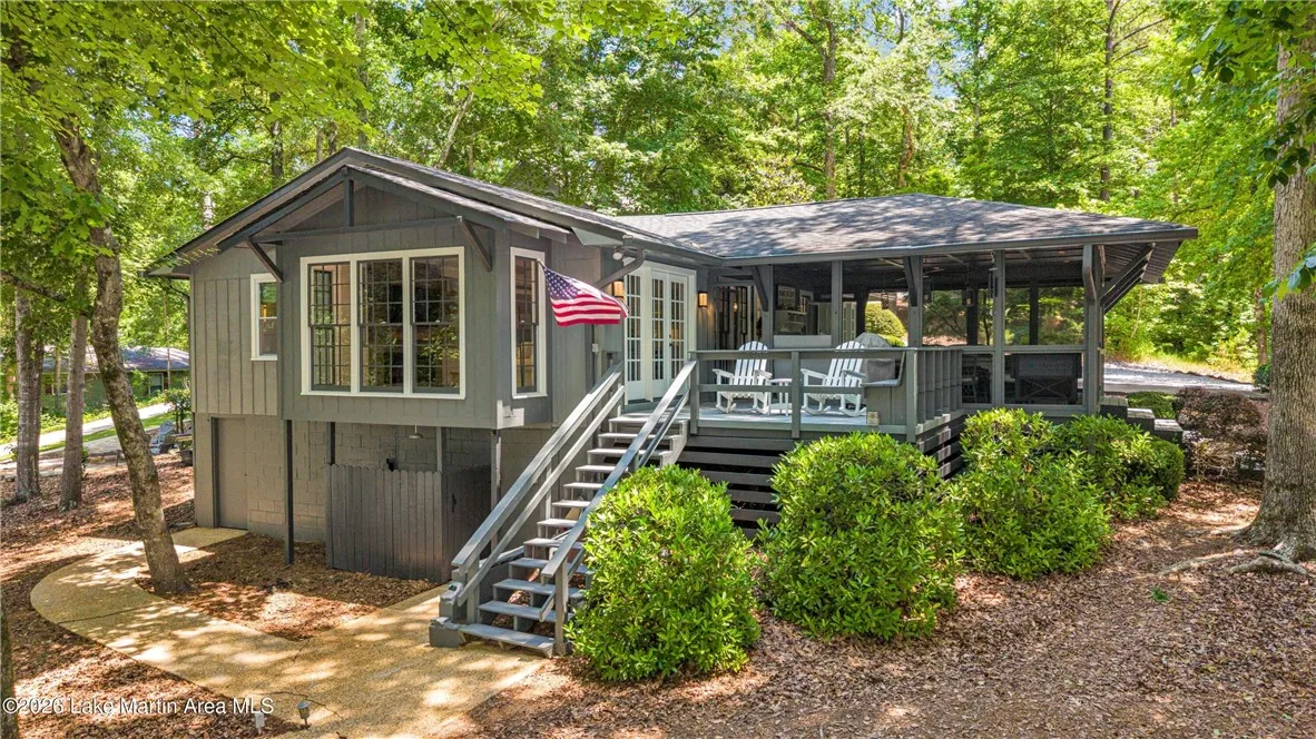 A welcoming home surrounded by mature trees, featuring a spacious screened porch and inviting outdoor steps.