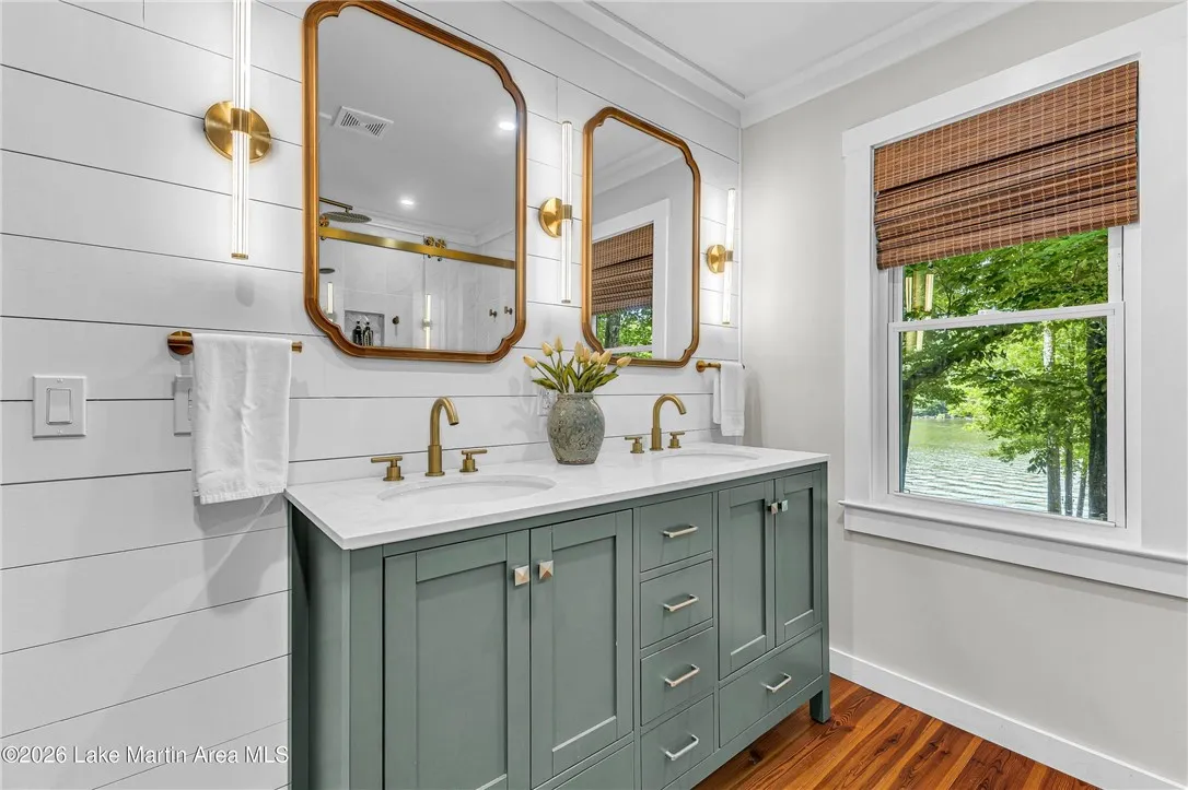 Double vanity with sleek fixtures offers a serene lake vista through the adjacent window.