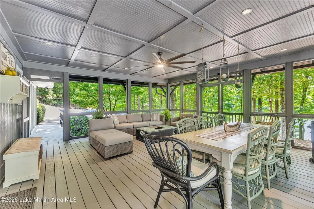 A spacious screened porch with dining and lounge areas offers serene views of the surrounding natural landscape.
