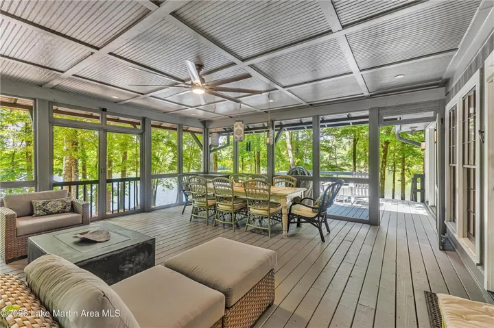 A spacious screened porch overlooks serene waters and lush woodlands, perfect for outdoor living.