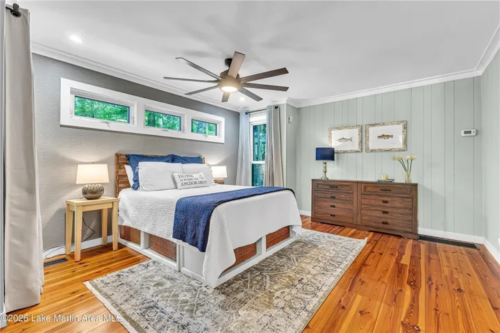 Sunlight fills this comfortable sleeping sanctuary, highlighting the rich hardwood flooring and elegant window treatments.