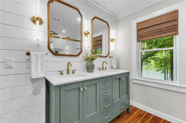 Double vanity with sleek fixtures offers a serene lake vista through the adjacent window.
