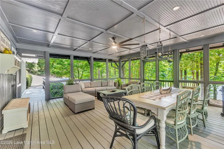 A spacious screened porch with dining and lounge areas offers serene views of the surrounding natural landscape.