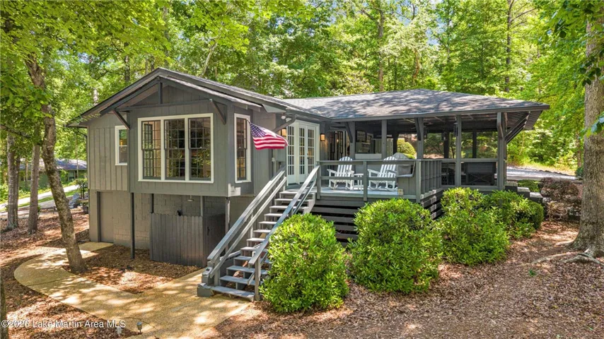 A welcoming home surrounded by mature trees, featuring a spacious screened porch and inviting outdoor steps.