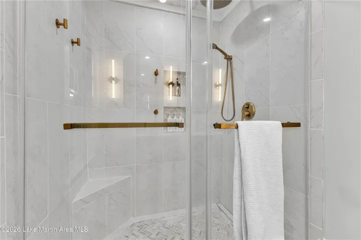 Luxurious walk-in shower with refined gold-toned fixtures and built-in shelving.