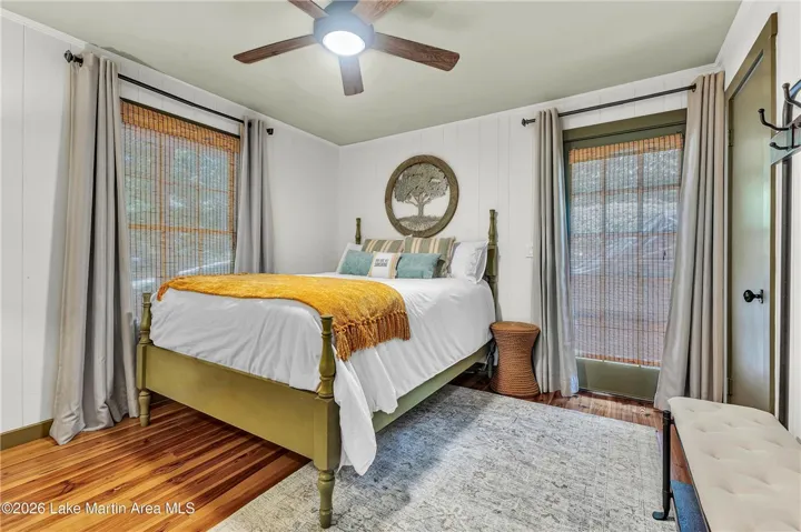 A restful chamber showcasing rich wood flooring and multiple windows for abundant light.