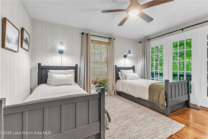 Two individual beds offer peaceful slumber within this charming bedroom featuring hardwood floors and direct outdoor access.
