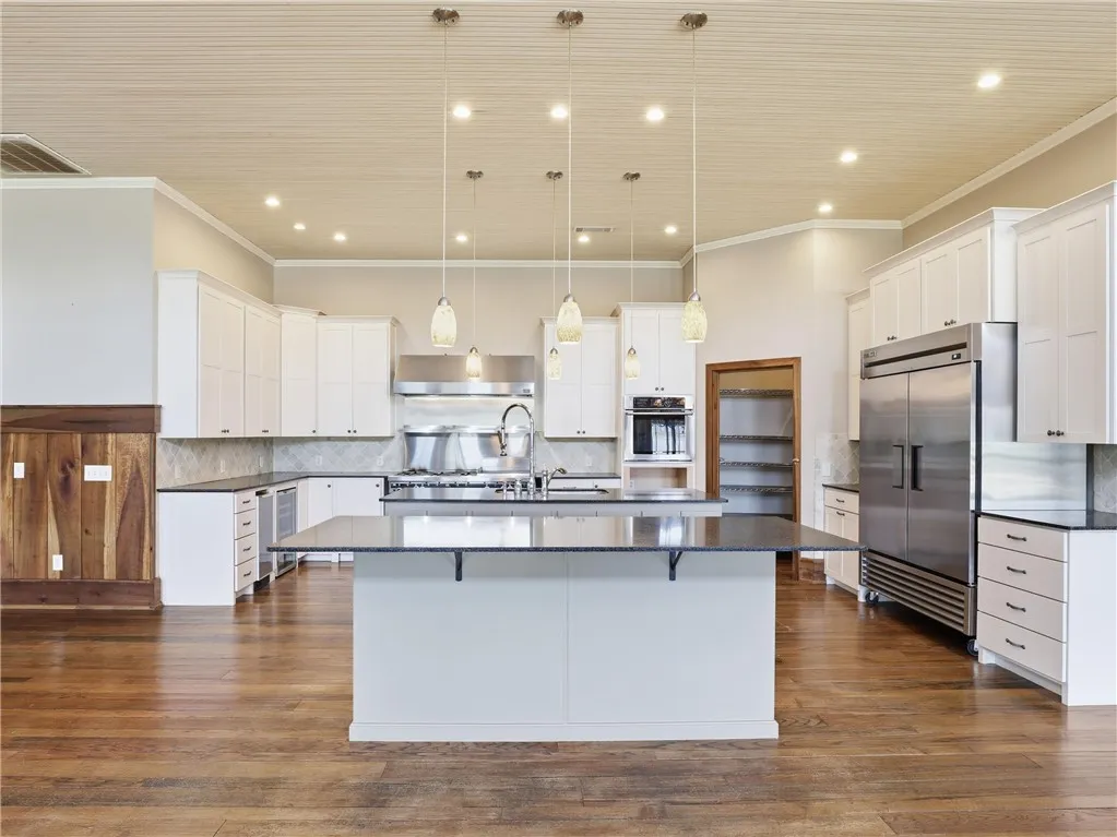 Culinary delights await in this spacious kitchen featuring a large central island and rich hardwood flooring.