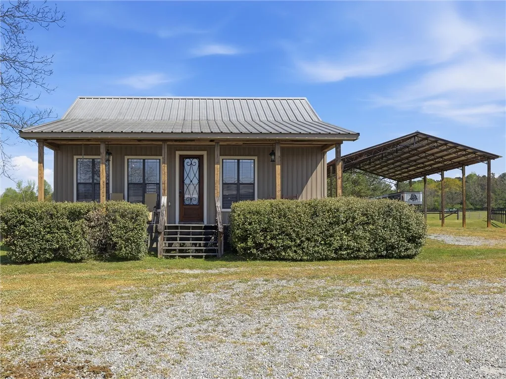 A charming country retreat with a welcoming covered porch and practical detached carport awaits.