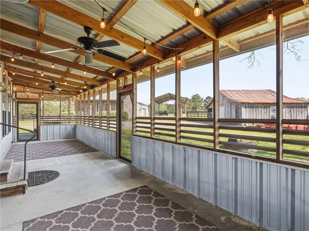 A spacious screened porch offers views of the surrounding rural landscape and outbuildings.