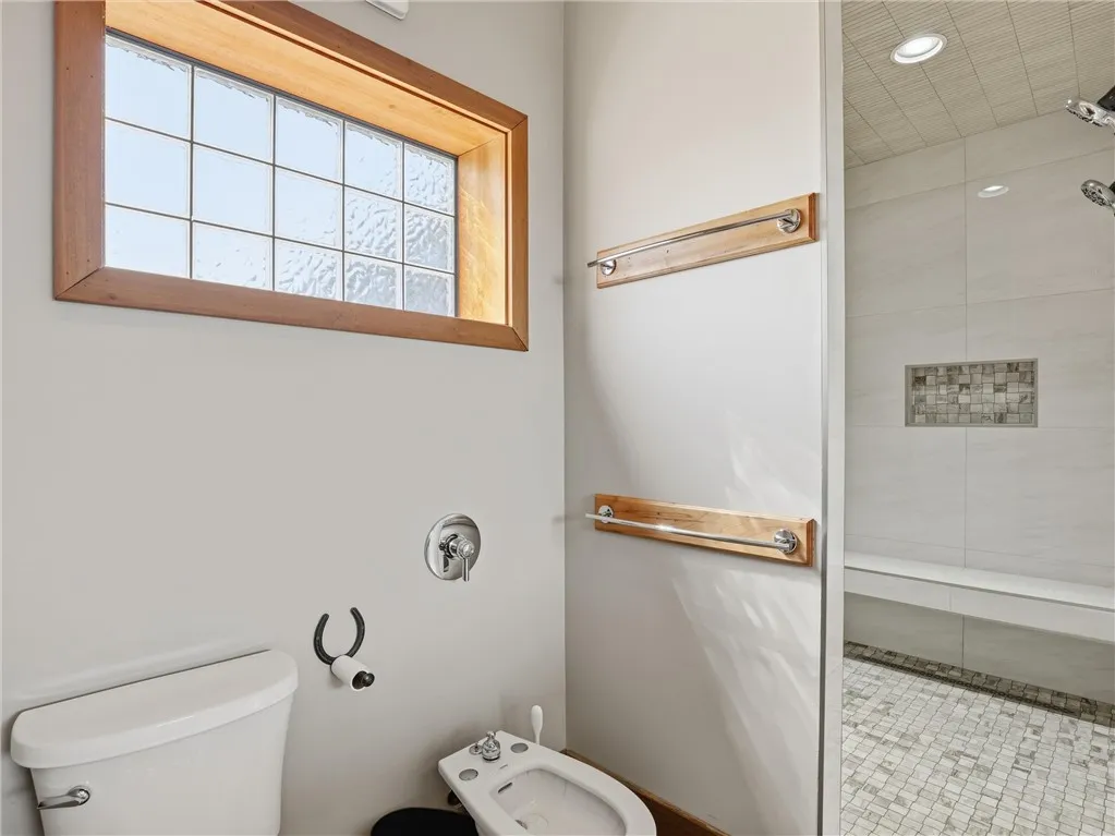 A well-lit, private bathroom offers a dedicated shower space alongside modern fixtures and a bidet.