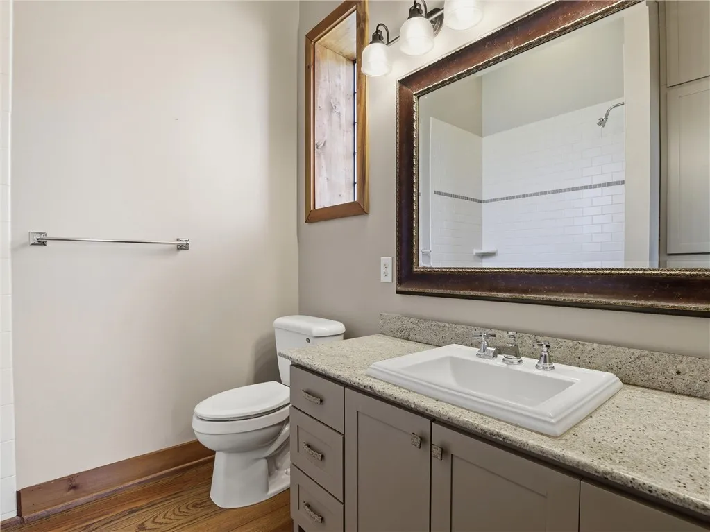 A refined bathroom features a single vanity, a spacious mirror, and a sleek toilet.