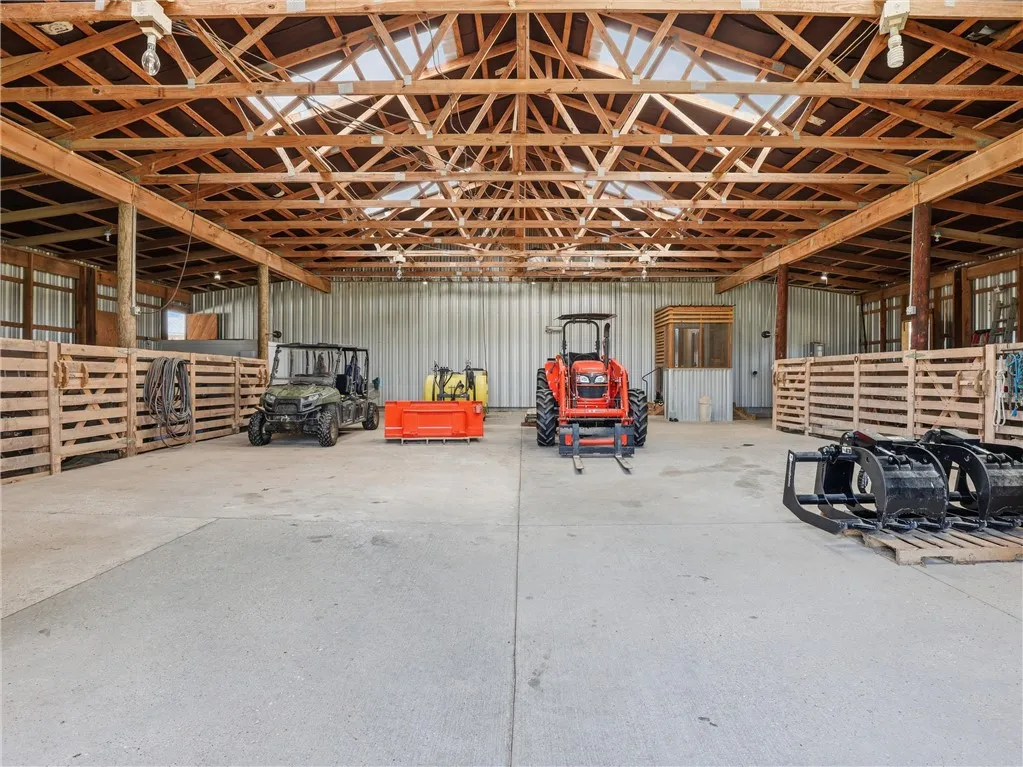 A spacious barn, ideal for equipment storage, features sturdy exposed wooden beams and a concrete floor.