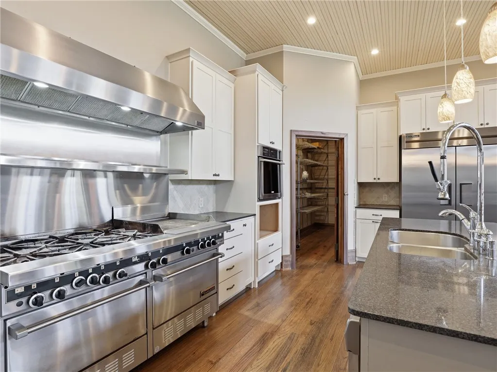A chef's dream kitchen features commercial-grade appliances, hardwood flooring, and a convenient walk-in pantry.