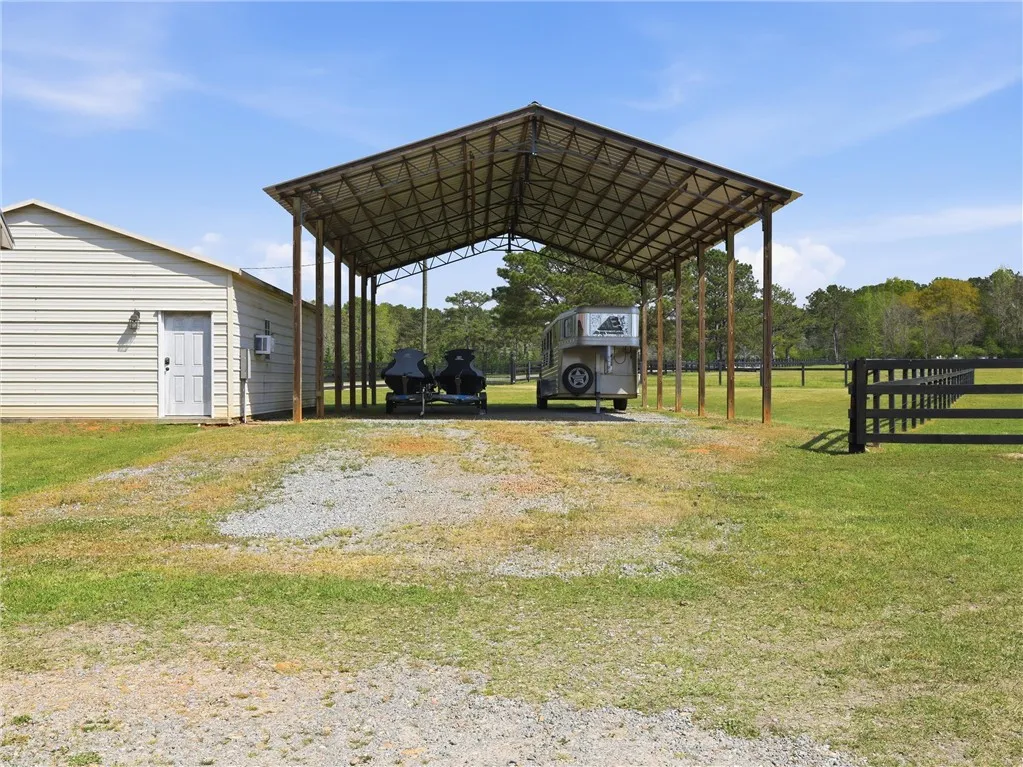 A spacious covered structure offers ample storage alongside a versatile outbuilding on this verdant property.