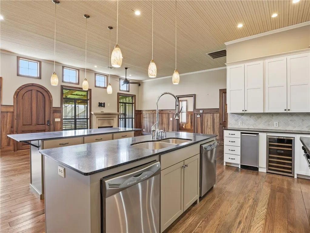 Dual kitchen islands with granite surfaces define this gourmet space, highlighted by pendant lighting and warm wood paneling.