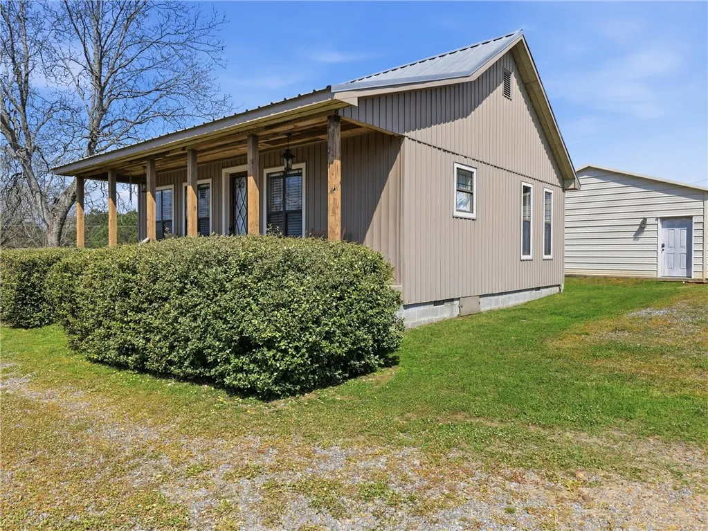 A charming country retreat with a welcoming covered front porch and mature landscaping.