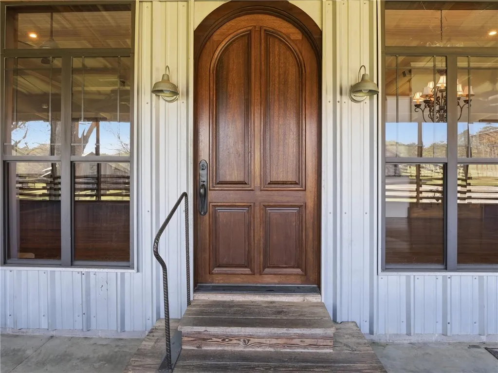 An arched wooden entry door welcomes guests to this corrugated metal home.