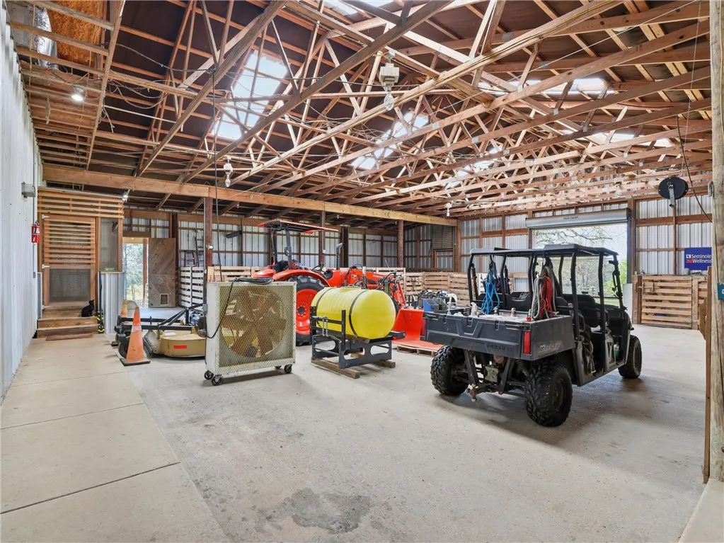 A spacious barn, ideal for equipment storage, features sturdy wooden beams and a wide entry point.
