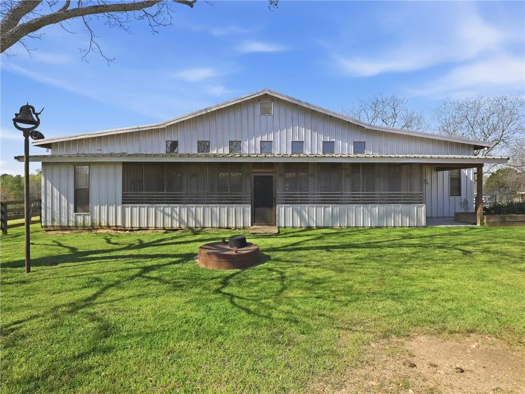 A spacious barn structure featuring a wide, screened-in porch and verdant lawn.