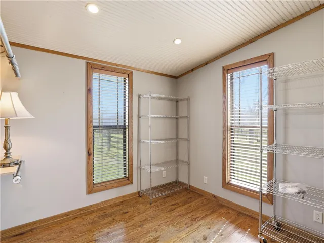 Natural light floods this versatile room, featuring rich hardwood floors and functional storage.