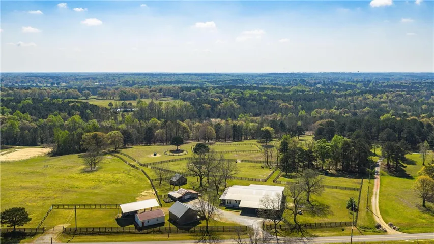 Sprawling acreage offers a secluded home, outbuildings, and fenced pastures amid a verdant landscape.