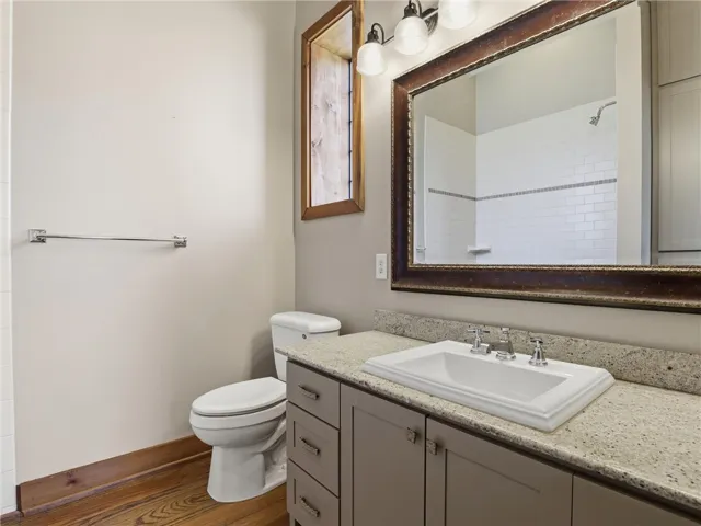 A refined bathroom features a single vanity, a spacious mirror, and a sleek toilet.