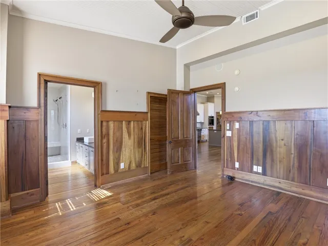 Rich hardwood floors complement detailed wood paneling, leading into an inviting kitchen space.
