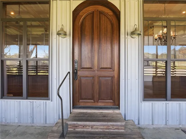 An arched wooden entry door welcomes guests to this corrugated metal home.