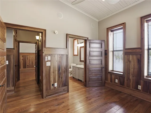 Rich hardwood flooring extends throughout this naturally illuminated space with wood paneling accents and direct bathroom access.