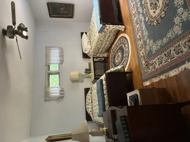 Hardwood floors and patterned rugs define this cozy sleeping space, complete with a window for natural light.