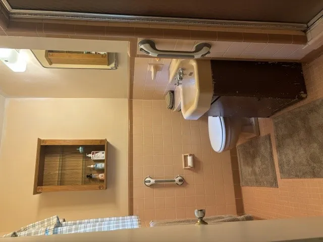 The bathroom features a combination of classic fixtures and tile, with a functional medicine cabinet for storage.