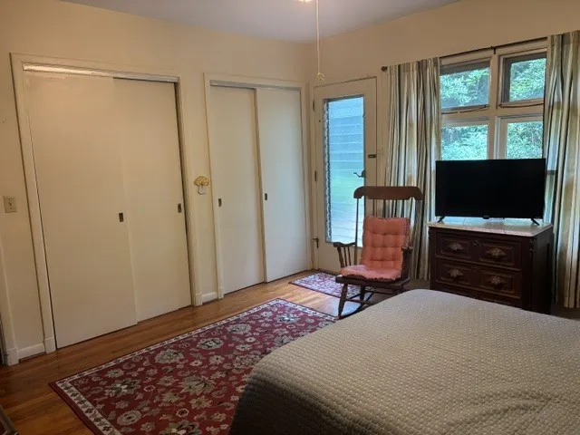 Well-lit bedroom with natural wood flooring and ample storage.