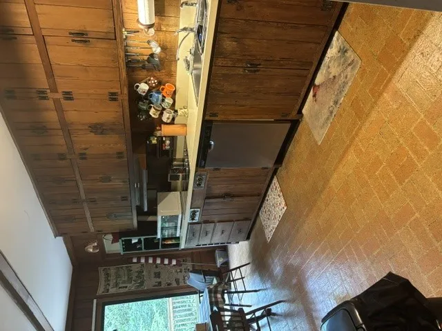 A warm kitchen features rich wood cabinetry and classic brick flooring.