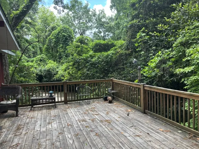A spacious wooden deck provides a serene outdoor retreat amidst lush, green foliage.
