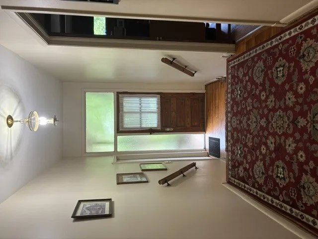 A welcoming entry features a rich wooden door with glass panels and a decorative red area rug.
