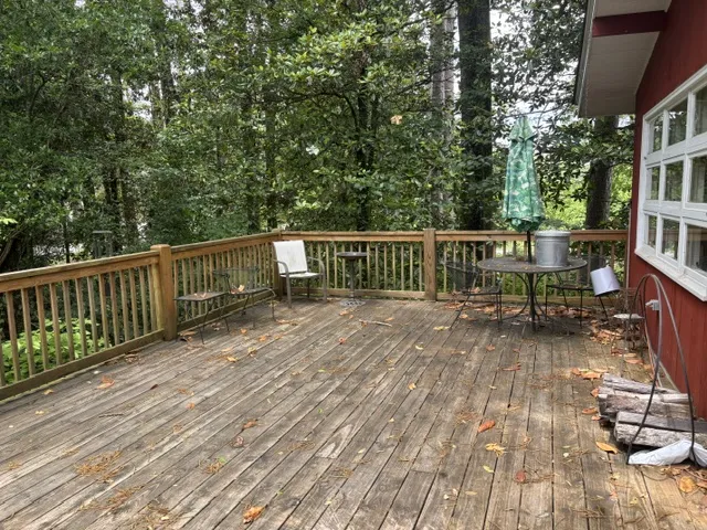A spacious wooden deck provides a serene outdoor living area, perfectly framed by verdant trees.