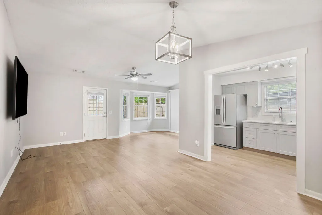 Blonde hardwood floors flow through this light-filled open-concept living area, leading to a modern kitchen.