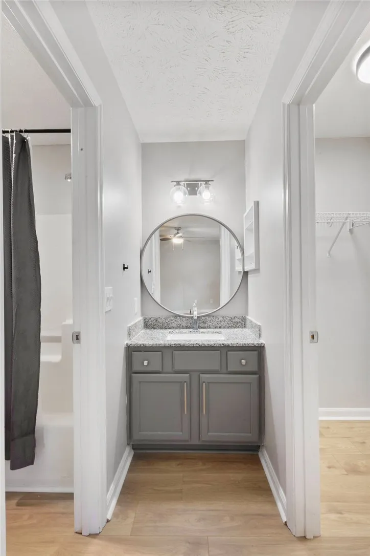 A well-lit bathroom vanity with granite counters, centered between a shower and a closet.