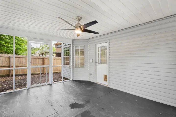 Relax in this screened porch with ceiling fan, offering a peaceful view of the fenced backyard.