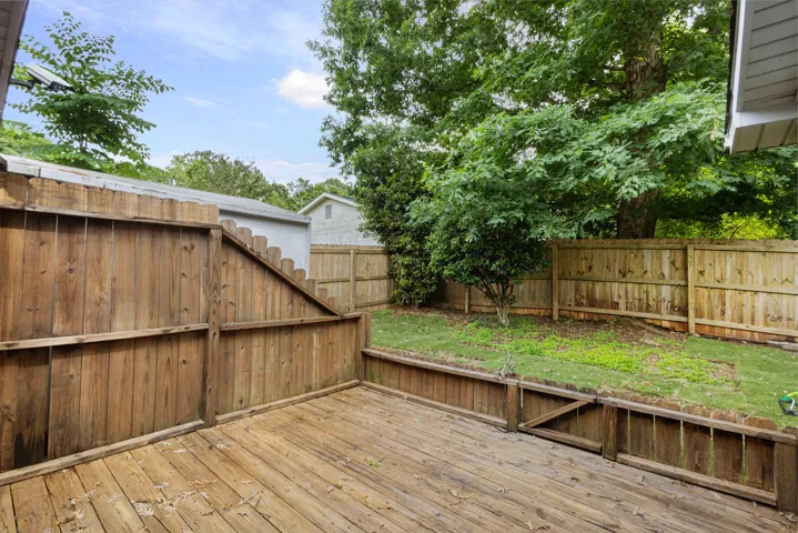 A private backyard oasis with a spacious wood deck and lush green lawn.